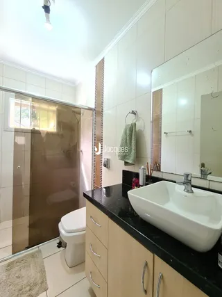 Foto de um banheiro moderno com bancada escura e revestimentos claros.
