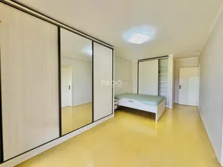 Quarto com armários brancos e espelhos em um ambiente claro.