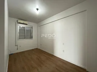 Ambiente interno com piso de madeira e parede branca.