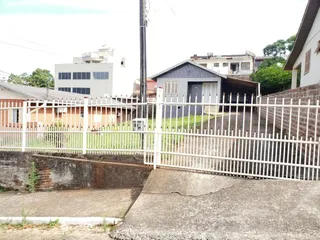 Vista externa de uma residência em Lajeado, Brasil, com cerca branca e vegetação.