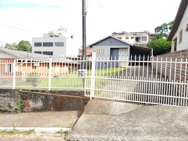 Vista externa de uma residência em Lajeado, Brasil, com cerca branca e vegetação.