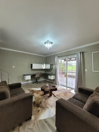 A sala de estar apresenta um ambiente com sofá e vista para o exterior.