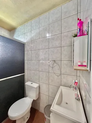 Foto de um banheiro com revestimento de azulejos brancos.