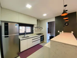 Cozinha moderna com armários brancos e bancada de mármore.