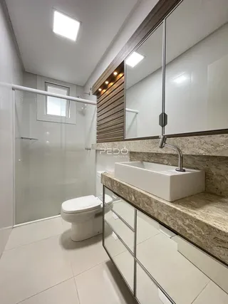 Banheiro moderno com box de vidro e bancada de mármore.