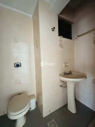 Banheiro com azulejos brancos e vaso sanitário.