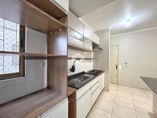 Cozinha com armários de madeira e piso claro.