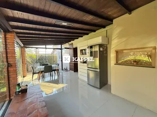 Ambiente aberto com cozinha e sala de jantar com vista para o exterior.