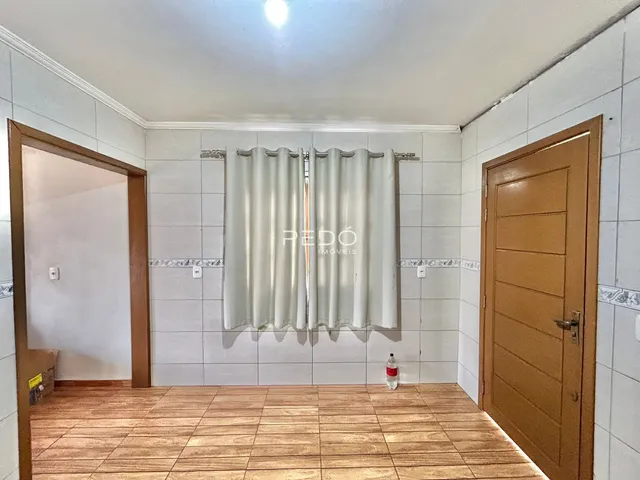 Ambiente interno de uma sala com piso de madeira e paredes brancas.