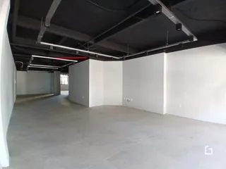 Espaço interno com estrutura de teto exposta e piso de concreto.