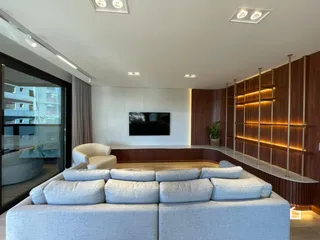 Sala de estar moderna com sofá e televisão em um ambiente bem iluminado.
