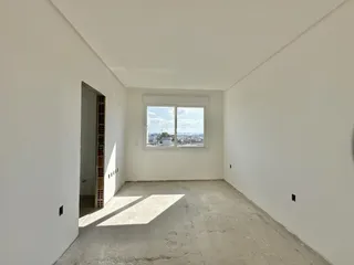 Interior de um espaço com paredes brancas e piso de concreto em uma residência.
