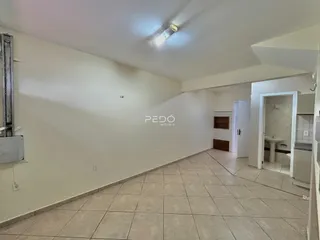 Vista interna de um corredor com piso de cerâmica clara.