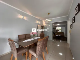 Foto de um ambiente de jantar com mesa escura e cadeiras estofadas em um apartamento.