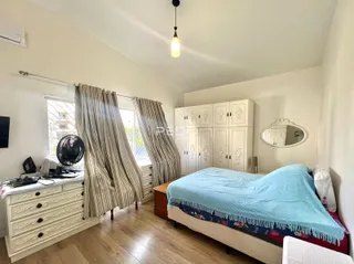 Quarto com armário branco e piso de madeira clara.