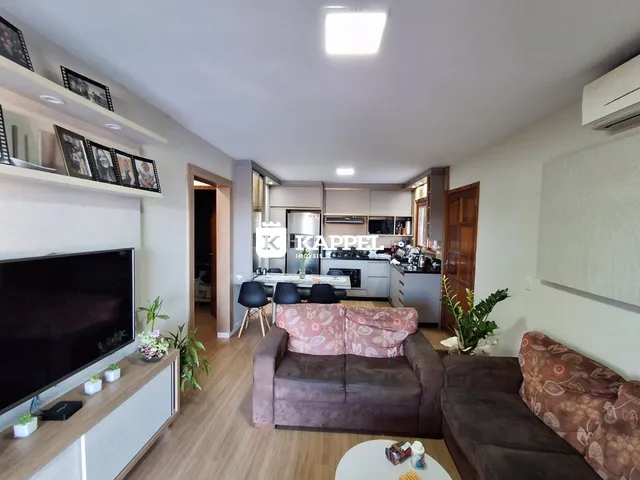 Sala de estar com sofá e televisão em um ambiente com piso de madeira.