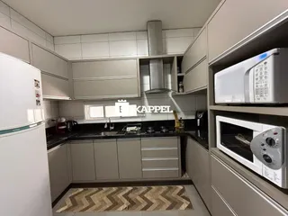 Esta é uma cozinha moderna com armários claros e bancadas escuras.