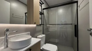 Banheiro moderno com bancada de mármore e box de vidro transparente.