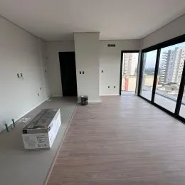 Ambiente interno com piso de madeira e grandes janelas que dão para a paisagem.
