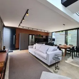 Foto interna de uma sala de estar com sofá e teto alto.