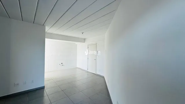 Um corredor longo com paredes brancas e piso de cerâmica.
