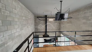 Vista de um corredor com parede de tijolos e grade de metal na área de uma residência.