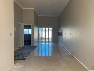 Corredor interno com piso reflexivo e portas de vidro que dão acesso ao exterior.
