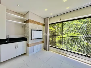 Vista interna de uma cozinha moderna com grandes janelas que oferecem uma vista para a natureza.
