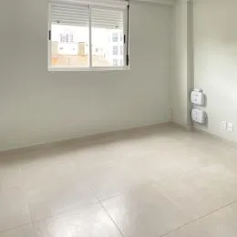 Ambiente interno vazio com piso claro e paredes brancas.