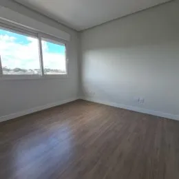 Vista de uma janela em um cômodo interno com piso de madeira.