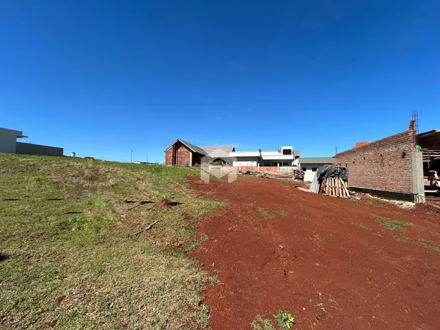 Vista externa de uma propriedade com terreno em terra vermelha e construção em andamento.