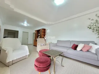 Sala de estar com sofá cinza e móveis de madeira clara.
