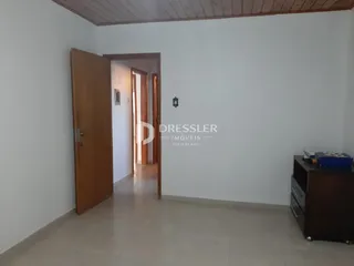 Hall de entrada com porta de madeira e parede branca.