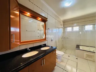 Vista de um banheiro com bancada escura e box de vidro
