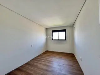 Vista interna de um ambiente com piso de madeira e paredes brancas.