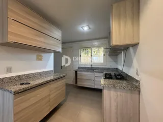 Cozinha moderna com armários de madeira clara e bancadas de granito.