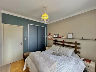 Quarto com cama e cabeceira de madeira em um ambiente claro.