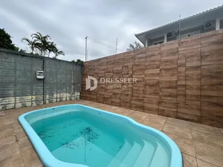 Foto de uma piscina externa com muro de revestimento marrom.