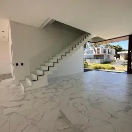 Vista de um hall com escadaria em um imóvel com piso de mármore claro.