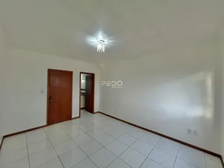 Vista interna de um ambiente com piso de cerâmica branca e porta de madeira.