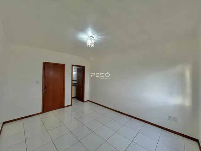Vista interna de um ambiente com piso de cerâmica branca e porta de madeira.