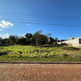 Vista de uma área gramada e campo aberto com árvores ao fundo.