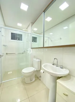 Foto de um banheiro moderno com box de vidro e azulejos claros.