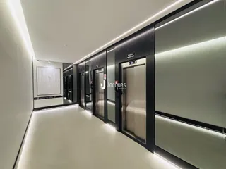 Corredor interno de um apartamento com elevadores e espelhos.