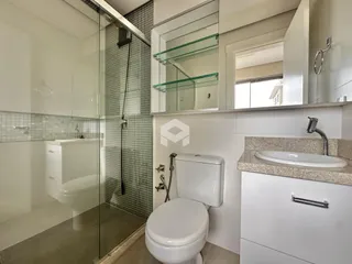 Foto de um banheiro com box de vidro e revestimento cerâmico.