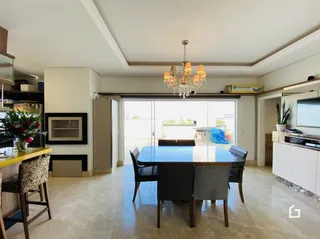 Uma sala de jantar com mesa de vidro e cadeiras.