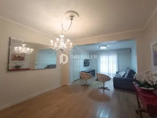 Sala de estar com piso de madeira e espelho refletindo o ambiente.