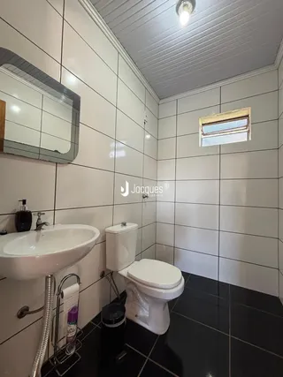 Foto de um banheiro com revestimento de azulejos brancos e piso escuro.