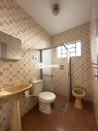 Foto de um banheiro interno com revestimento de parede e louças sanitárias.
