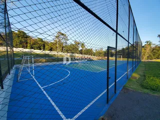 Imagem de um campo esportivo externo azul cercado por tela.